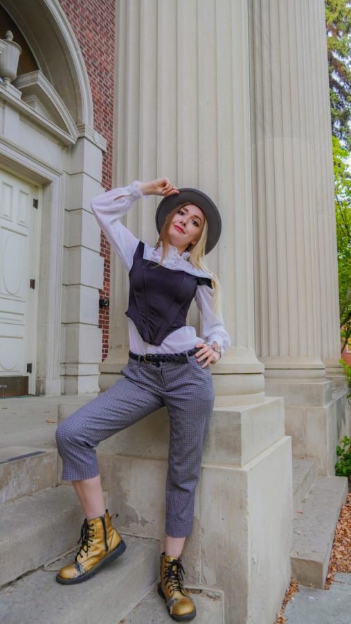 Katherine models her grandmothers shirt, a silk corset style off-shoulder top from Etsy, braided belt from Etsy and slacks/hat from Goodwill in Ellensburg. Shoes are reflective gold boots from Old Skools record store on Main. Photo shot in front of McConnell Hall.