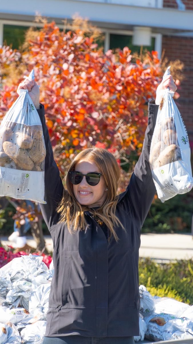 Dania Cochran, executive liaison for the presidents office, carries bags of potatoes to a vehicle